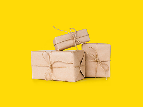 Three gifts wrapped in kraft paper tied with twine against a yellow background.   