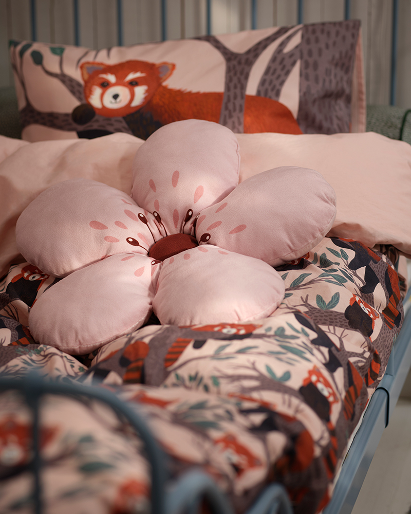 Un cojín de ALPTALL con un estampado de flores rosas sobre la ropa de cama de ALPTALL en la habitación de un niño.
