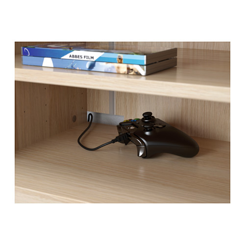El controlador de juegos negro se encuentra en un estante de madera al lado, el cable pasa por el orificio.
