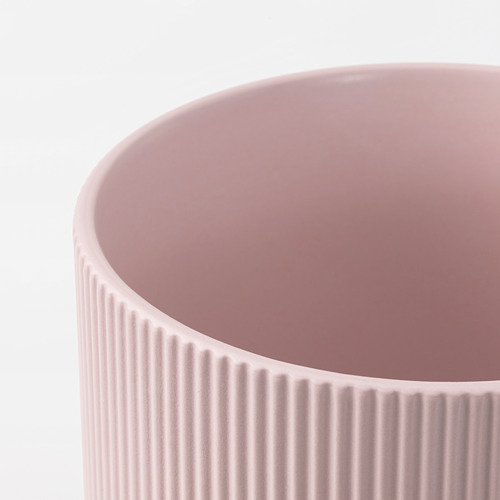 Primer plano de un jarrón liso de gres rosa con ranuras verticales, que muestra su fina textura y artesanía.