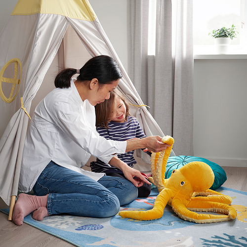 La mujer y el niño juegan en el interior con un pulpo de peluche. Están dentro de una tienda de campaña, disfrutando de la aventura fingida.
