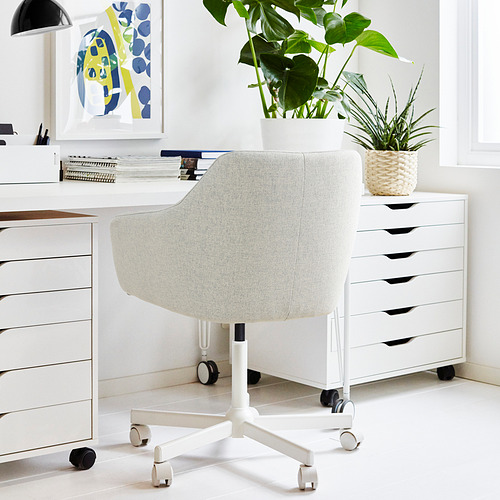 Moderno montaje de oficina en casa con silla TOSSBERG, blanco. La silla es ergonómica con ruedas, colocadas entre los cajones blancos y el escritorio. Las plantas añaden verdor.