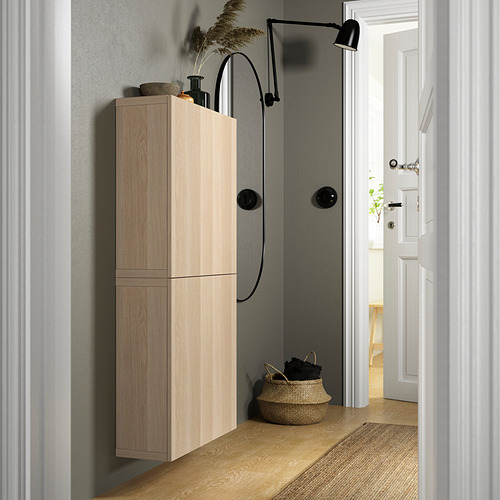 Mueble de madera BESTÅ con asas negras, lámpara de pared, cesta de mimbre, alfombra.