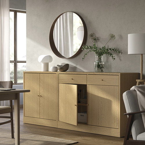 Salón moderno: aparador de madera, espejo redondo, lámpara blanca, silla, flores.