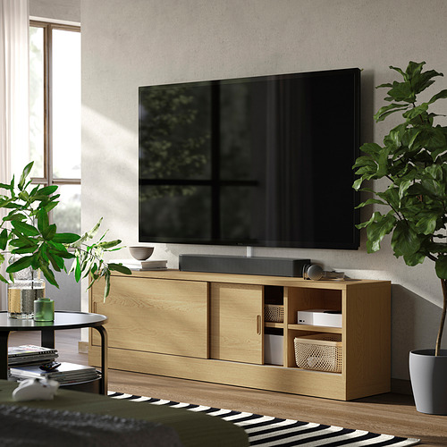 Gran mueble de tv TONSTAD con acabado de madera lisa, con puertas correderas y estantes abiertos, colocado contra una pared con un televisor de pantalla plana en la parte superior.