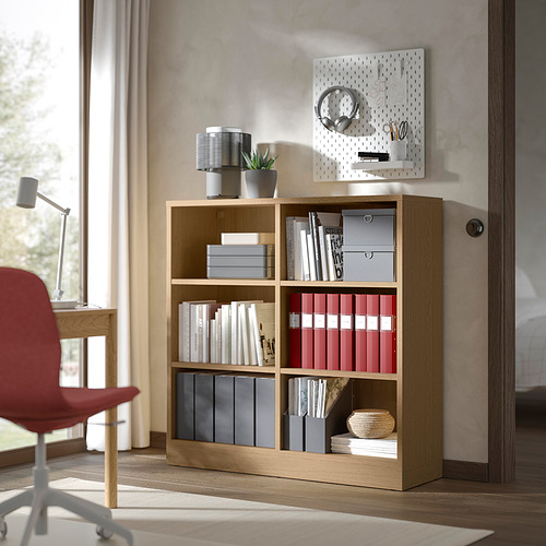 Estantería de madera con libros cerca de una ventana.