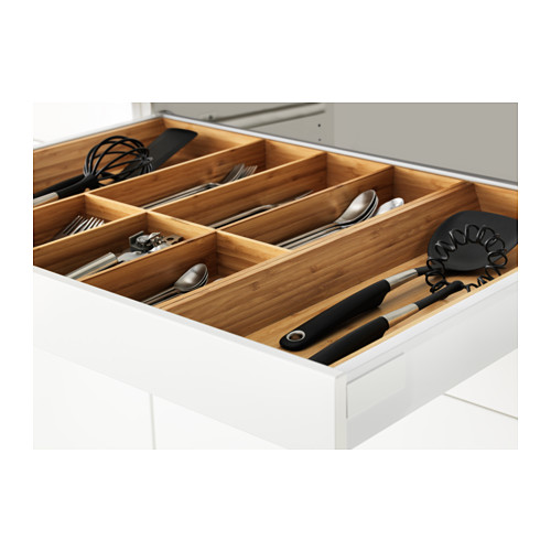 Organizador de cajones de madera en mueble de cocina blanco, sujeción de utensilios y utensilios de cocina, con cajones de cierre automático.