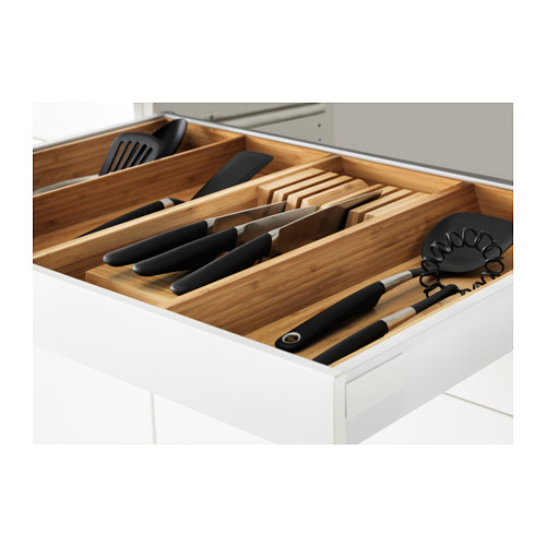 Organizador de cajones de madera lleno de cuchillos, utensilios en un cajón blanco.