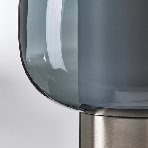 Primer plano de una moderna lámpara de mesa de cristal con un diseño elegante y pantalla de color humo.