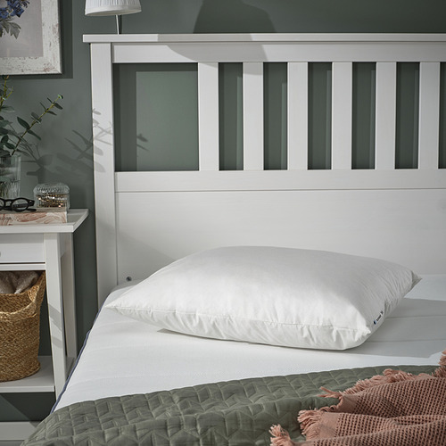 Almohada PILSPINNARE en edredón blanco sobre verde, afelpada, cómoda, en cabecero.