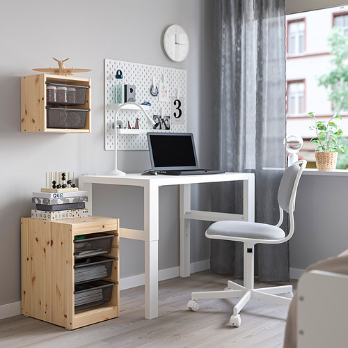 Acogedora oficina en casa con unidades de almacenamiento TROFAST, escritorio blanco, silla gris y estantes de madera. El escritorio tiene una computadora portátil y un tablero de clavijas con notas y decoraciones.