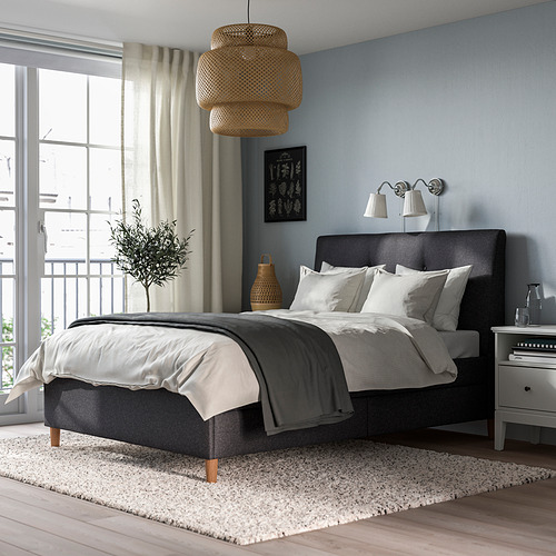 Dormitorio minimalista con cama IDANÄS, lámpara colgante, apliques de pared, ropa de cama gris, ventana grande, jarrón, jarra.