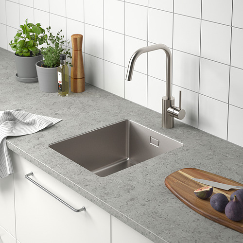 Fregadero de cocina moderno con grifo de acero inoxidable, tabla de cortar, frutas y hierbas.