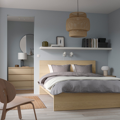 Dormitorio azul con cama MALM, ropa de cama gris, lámpara colgante, mesa auxiliar y estante de pared.