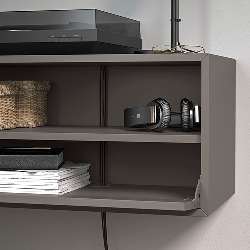 Un moderno mueble de almacenamiento montado en la pared con estantes abiertos para libros y artículos. Uno de los estantes tiene a la vista un inteligente sistema de gestión de cables.