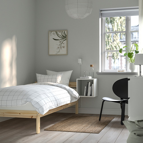 Dormitorio minimalista con cama NEIDEN de madera, ropa de cama blanca, paredes azules, estantería flotante, vista verde, arte abstracto, silla negra, alfombra de yute.