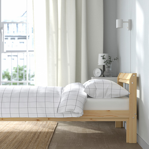 Una cama doble con estructura de madera y ropa de cama de rejilla blanca junto a una ventana.