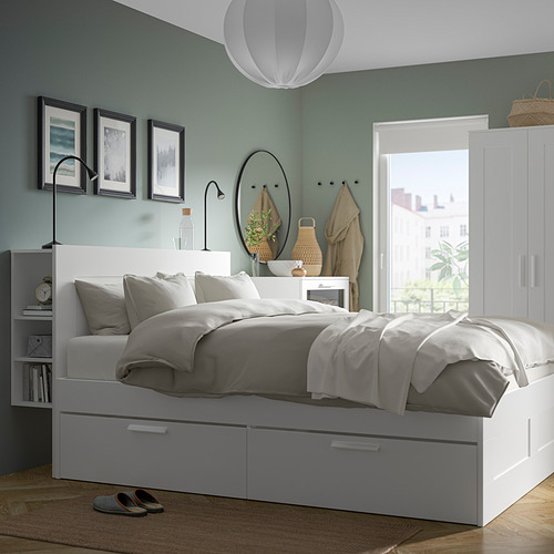 Dormitorio moderno con paredes azul claro, cama blanca, ropa de cama gris, lámparas NÄVLINGE y ventana con vista a la ciudad.