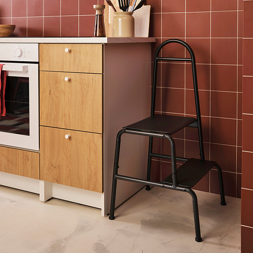 Cocina con taburete de 2 escalones BÄSINGEN negro, estructura de metal gris oscuro, armarios de madera y azulejos rojos.