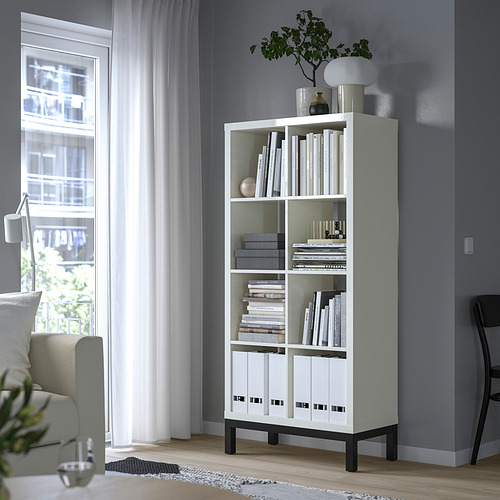 Estantería blanca KALLAX junto a ventana, libros, decoración, silla.
