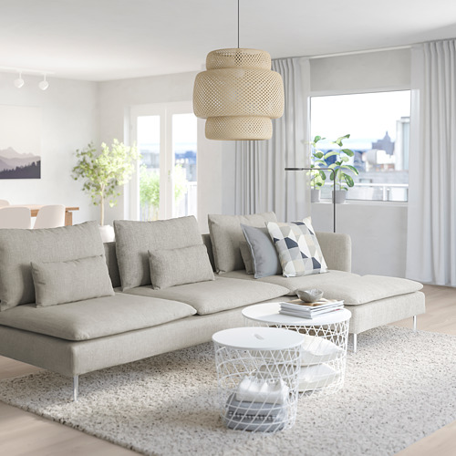 Sala de estar moderna con un gran sofá seccional SÖDERHAMN en blanco roto, cojines geométricos grises, lámpara colgante de mimbre apilada y ventanas con vista a la ciudad.