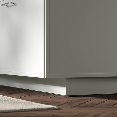 Cocina moderna con gabinetes blancos y grises. El zócalo blanco de ASPUDDEN llena el hueco, diseñado sobre piso de madera.