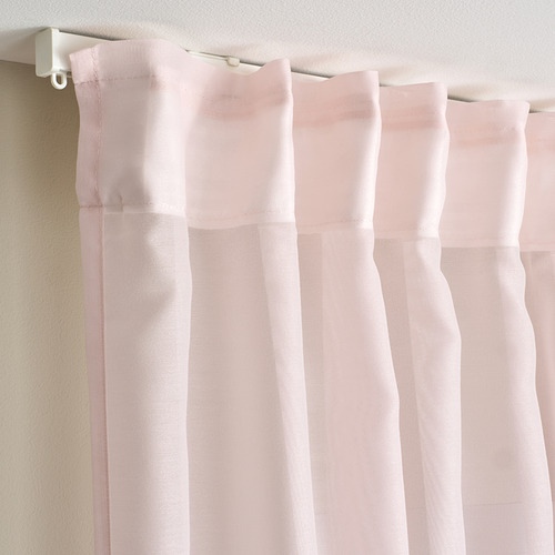 Las cortinas transparentes de color rosa claro cuelgan con pliegues, difundiendo el sol, ofreciendo privacidad durante el día.