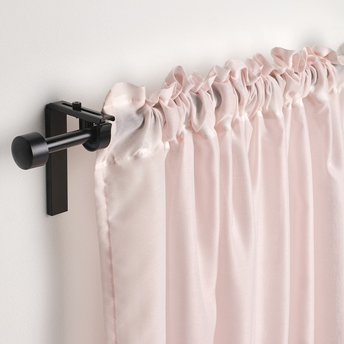 Las cortinas transparentes rosas cuelgan de una varilla negra con ganchos, difundiendo la luz y agregando suavidad a la ventana.