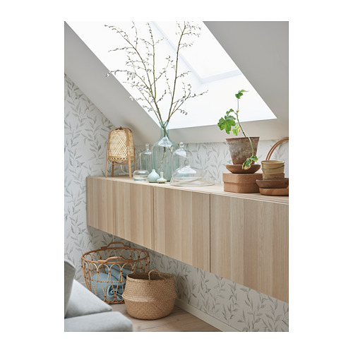 Sala de estar moderna con muebles de madera, jarrones, cestas y papel tapiz con motivos de hojas.
