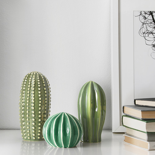 Tres cactus de cerámica en un estante, que se asemejan a plantas reales, agregan vegetación decorativa al hogar.