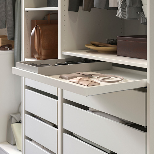 Organizador de armario KOMPLEMENT blanco con bandeja deslizable que sostiene carteras y accesorios, rodeado de ropa y una bolsa para colgar.