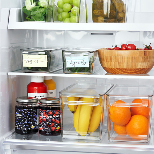 Nevera con frutas y frascos organizados, utilizando recipientes apilables transparentes con tapas y etiquetas para mayor frescura y fácil acceso.
