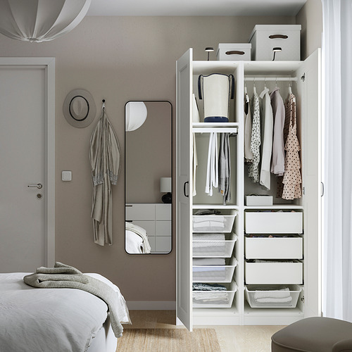 Dormitorio ordenado con armario abierto que muestra ropa organizada, cajones y cestas de malla. Las perchas y las cajas mantienen los artículos ordenados y visibles.