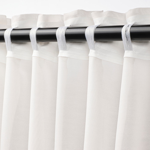 Cortinas blancas con tapa fruncida, que difunden la luz de la habitación.