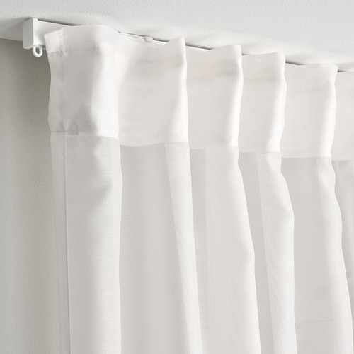 Cortinas blancas transparentes colgaban de ganchos, difundiendo la luz del día, proporcionando privacidad con una sensación fresca y aireada.