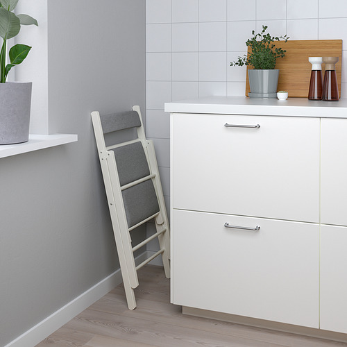 Taburete de cocina plegable con asientos y respaldo acolchados, apoyado en armarios.