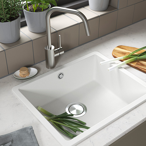 Fregadero de cocina moderno con grifo de acero inoxidable, cebollas verdes, encimera de cuarzo y accesorios.