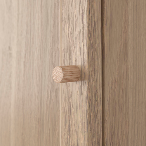 Vista de cerca de un mueble de madera clara con tirador cilíndrico.