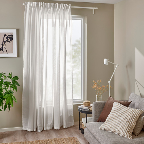 Sala de estar con cortinas transparentes, sillón, arte, paredes beige.