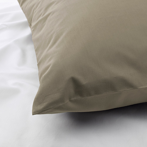 Primer plano de una funda de almohada lisa y de alta calidad que muestra un tejido nítido y apretado y una textura lujosa, colocada sobre ropa de cama blanca.