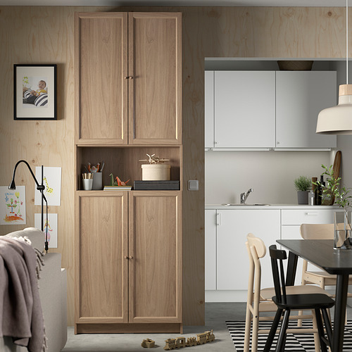 Sala de estar moderna con estantería BILLY, elementos decorativos, área de cocina y cálidas paredes de madera.