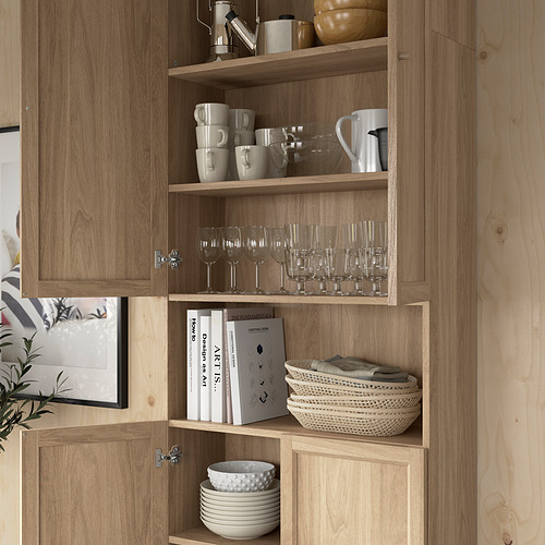 Estantería de madera con cristalería, tazas, libros y cuencos cuidadosamente organizados en estantes.
