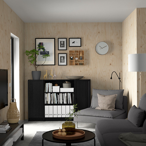 Salón minimalista con librería BILLY, sofá gris, paredes de madera y decoraciones.