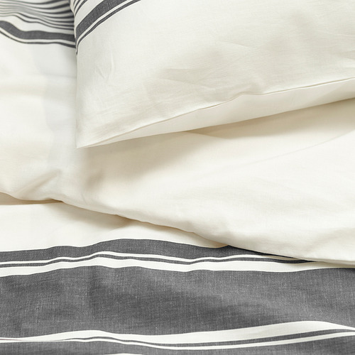 Sábana y fundas de almohada a rayas en blanco y gris, algodón nítido, cuidadosamente superpuestas, patrón de rayas visible.