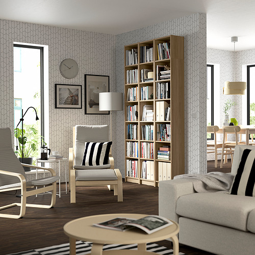 Salón moderno con librería BILLY, madera clara, estantes regulables, amplio, junto a sofá gris y sillas de rayas.