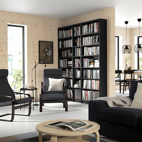 Habitación con gran librería BILLY, sillón, mesa de centro, zona de comedor y lámparas colgantes.