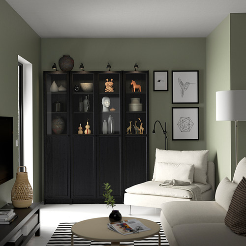 Sala de estar moderna con estantería BILLY, sofá blanco, mesa de centro de madera, pared de acento verde, impresiones artísticas, lámparas, plantas.