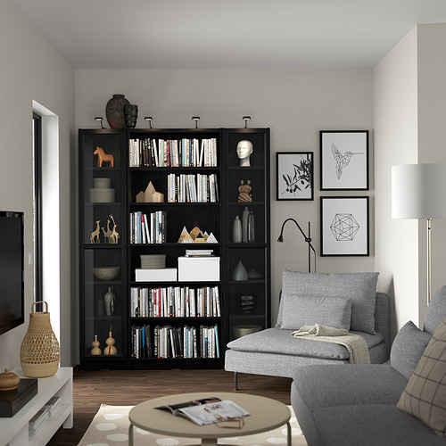 Sala de estar moderna con estantería negra BILLY, sofá gris y lámpara.