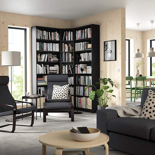 Sala de estar moderna con estanterías negras BILLY, muebles grises, ventanas grandes, asientos acogedores y detalles verdes.