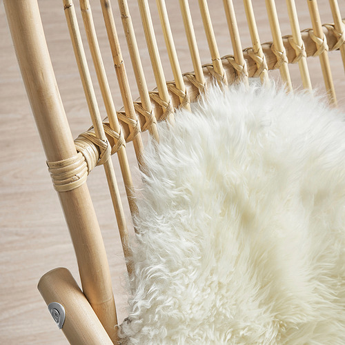 La imagen muestra un sillón de ratán tejido a mano con un cojín blanco esponjoso, que destaca el diseño natural y resistente.